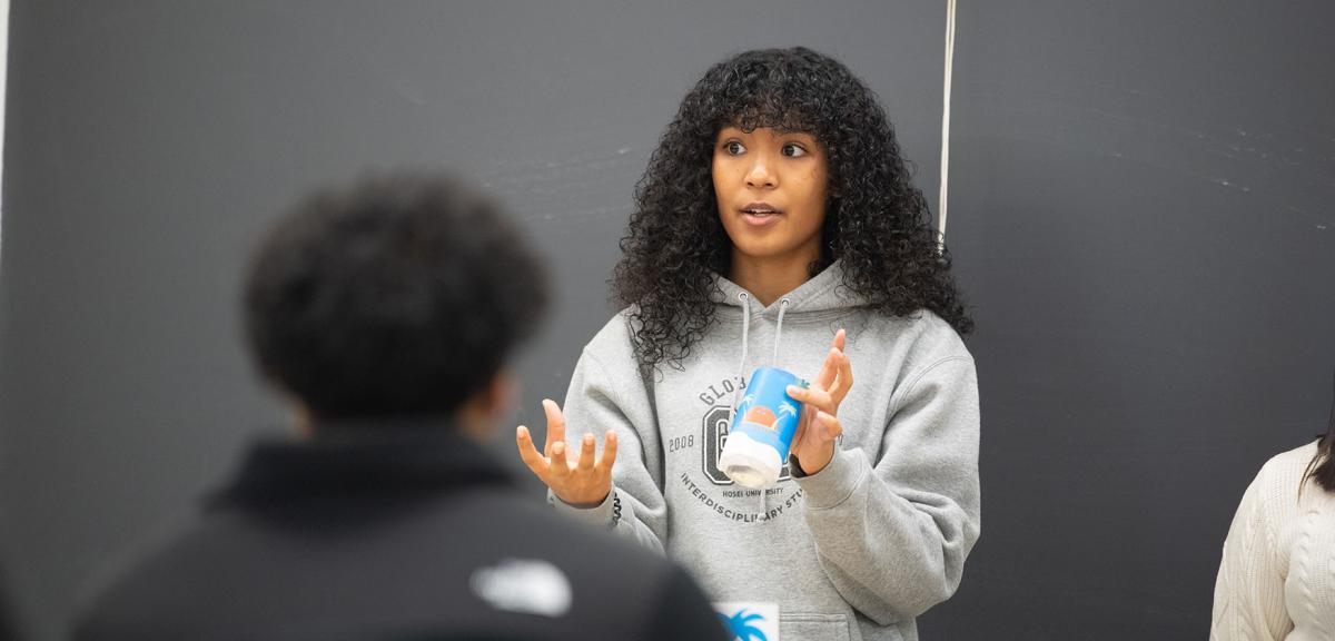 A student stands at the front of a class to give a presentation.