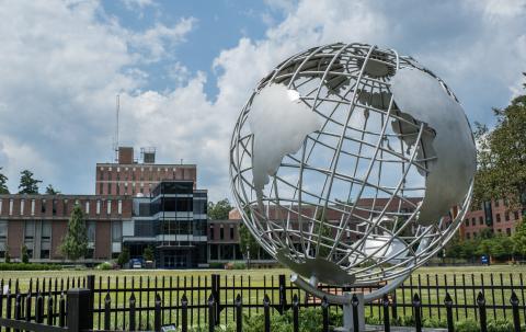 The globe sculpture on the campus green with the Ely Campus Center in the background