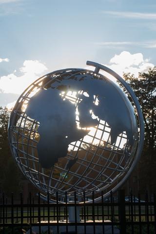 Sunlight shines through the globe sculpture on the campus green