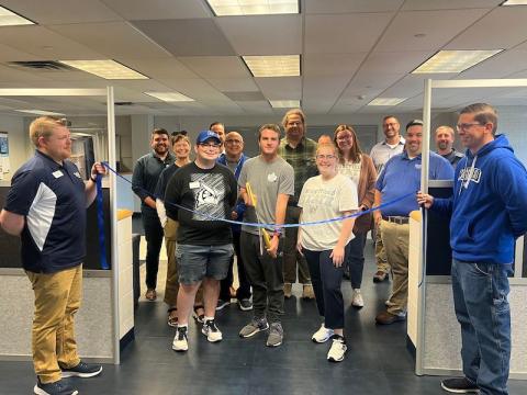 Matt Dellea, Jack Guindon, and Joshua Hattrick cutting a blue ribbon in front of the new commuter lounge.