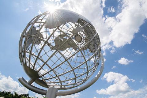 A close-up shot of the campus globe, backlit by a cloudy, blue sky.