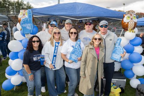 Alumni stand in front of decorated Homecoming tent