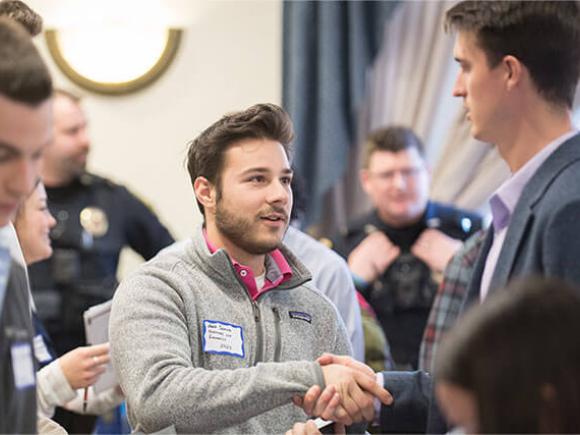 A student shakes hands with someone at a networking event.