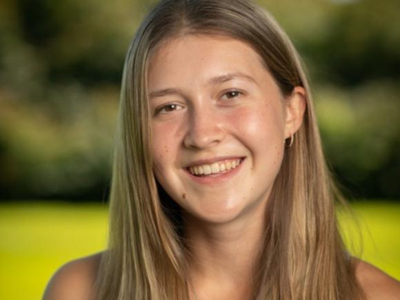 Student tour guide Shea Hamel. She is smiling and standing in an open field, with the background blurred behind her. 