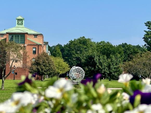 A campus stock photo of the globe. Blurred out flowers are posed in front of it.