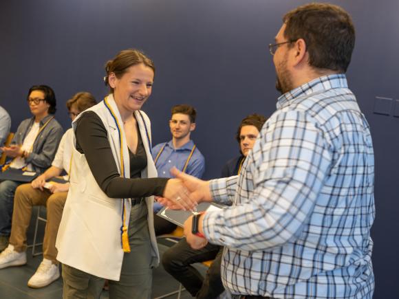 Student shaking hands with a faculty member at the Economics Department honors event.