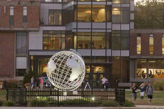 The metal globe sculpture on the Westfield State University campus is lit by spotlights at dusk.