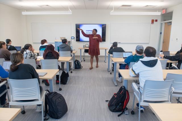 Teacher at the head of classroom in front of students