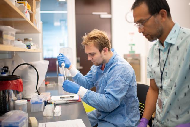 Student in biology lab working with faculty member on DNA extraction.