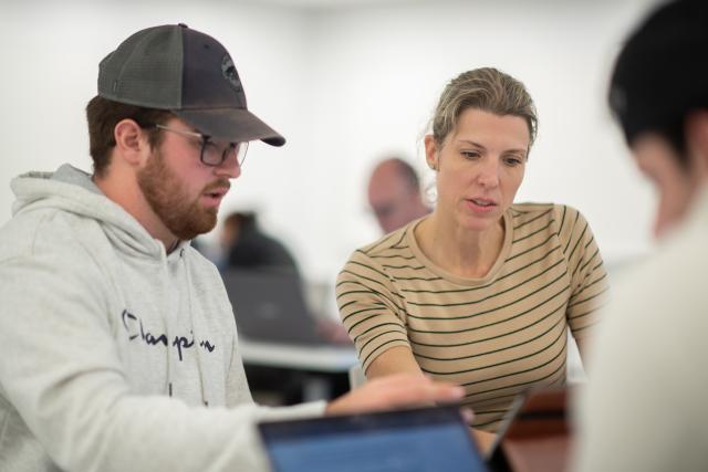 Faculty member working one-on-one with a student in a classroom, providing personalized guidance and support.