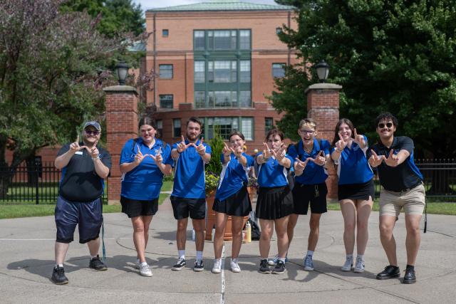 Students smiling during Welcome Week while holding up a ‘W’ hand sign for Westfield State.