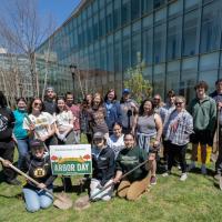 Arbor Day 2024. A group of students congregate around a white sign which says "Arbor Day" in front of the Nettie Science Building on campus. Professor Tim Parshall is with them. Two students in the front hold shovels.